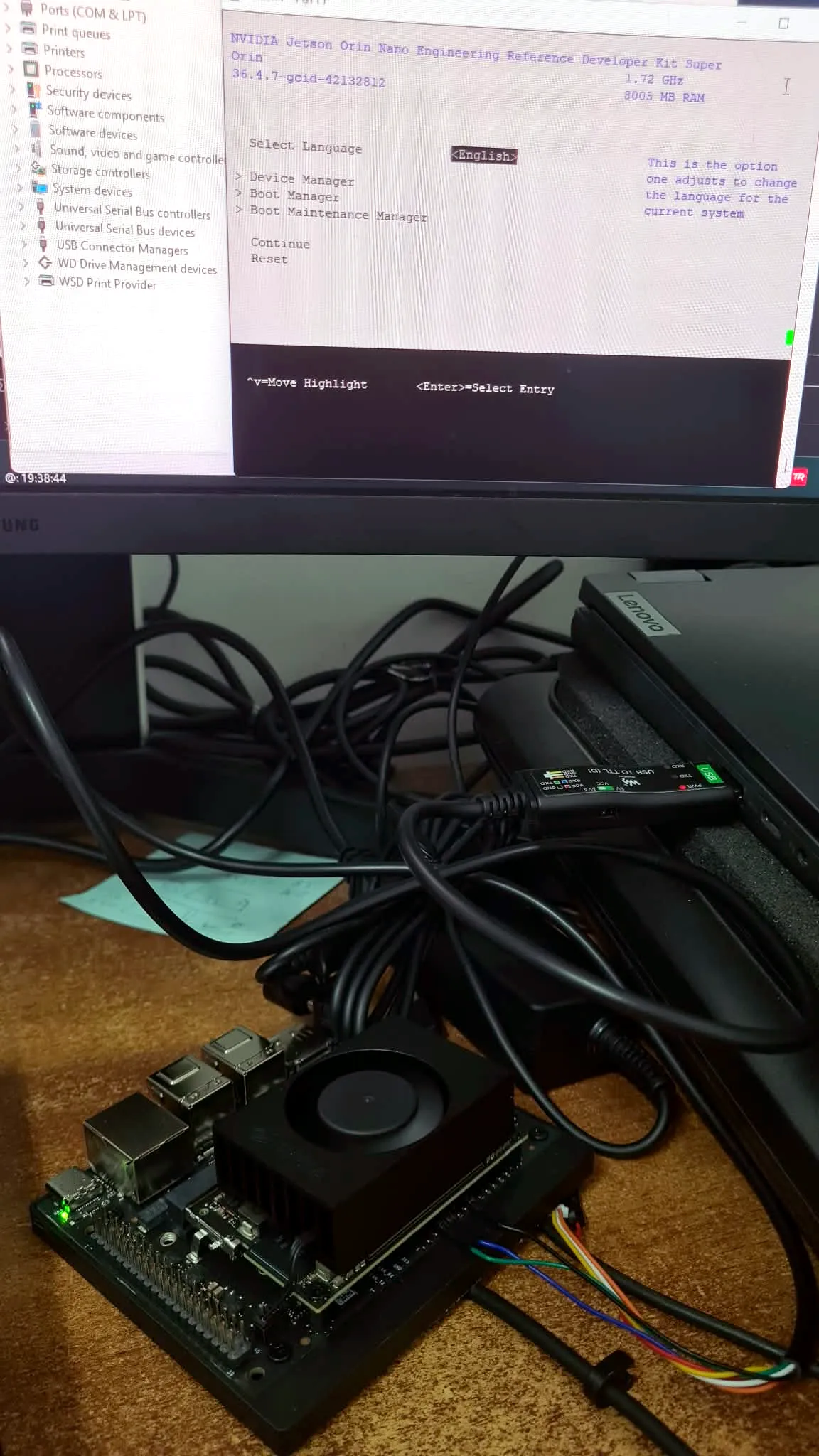 A Jetson Orin Nano developer board on a desk with a USB-to-serial cable wired into a small header, connected to a laptop, with the board's firmware menu showing on the monitor above
